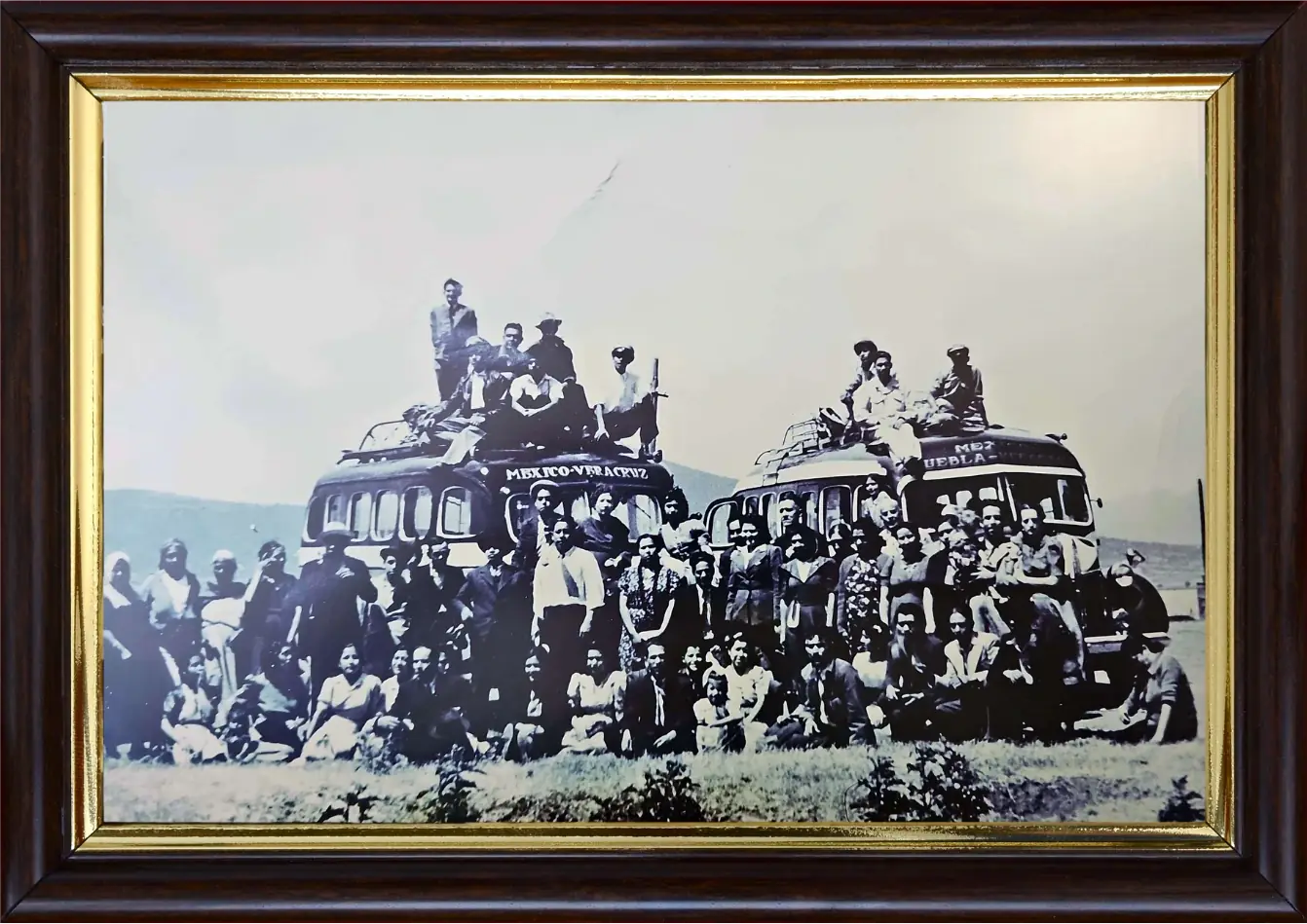 Fotografía de grupo de los años cuarenta: dos autobuses rotulados «México-Veracruz» y «Puebla-Veracruz» con una multitud de viajeros posando delante y varios sentados sobre el techo
